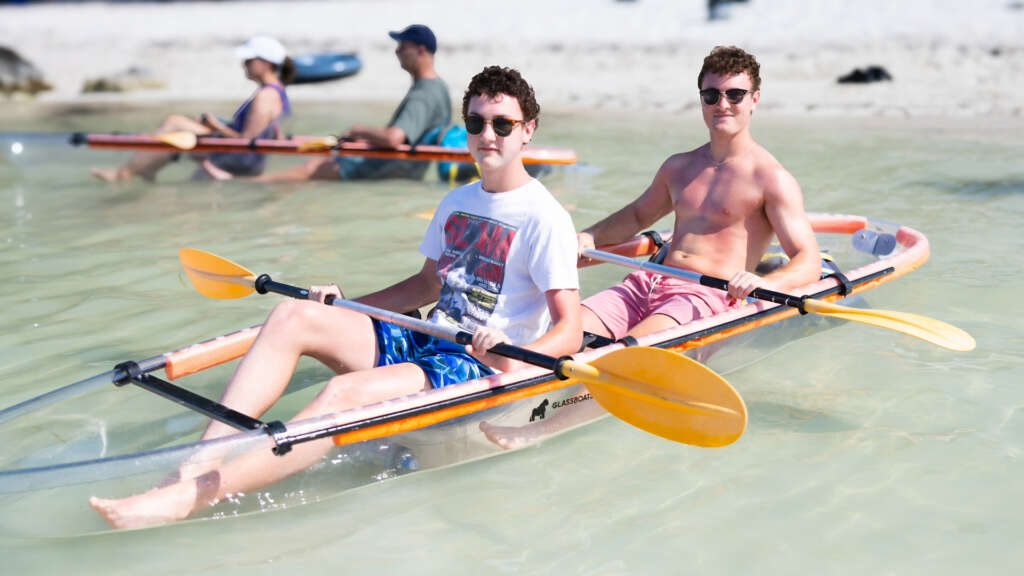 Two young adults preparing to embark on a clear kayak adventure to explore sandbars and mangrove tunnels.